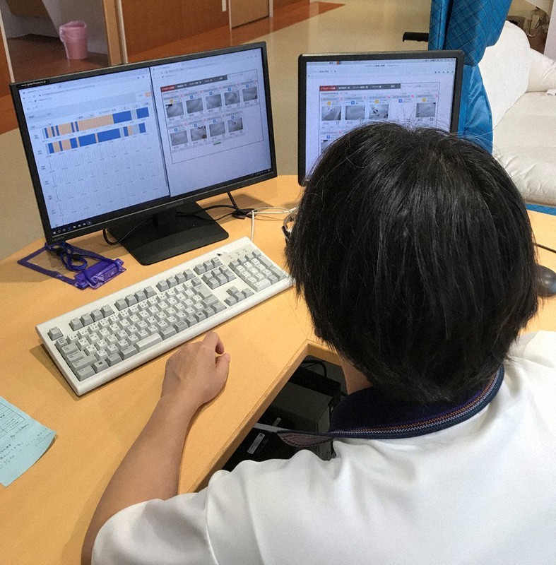 見守りセンサーが設置された居室の様子を端末の画面越しに確認する職員=好日苑大里の郷提供