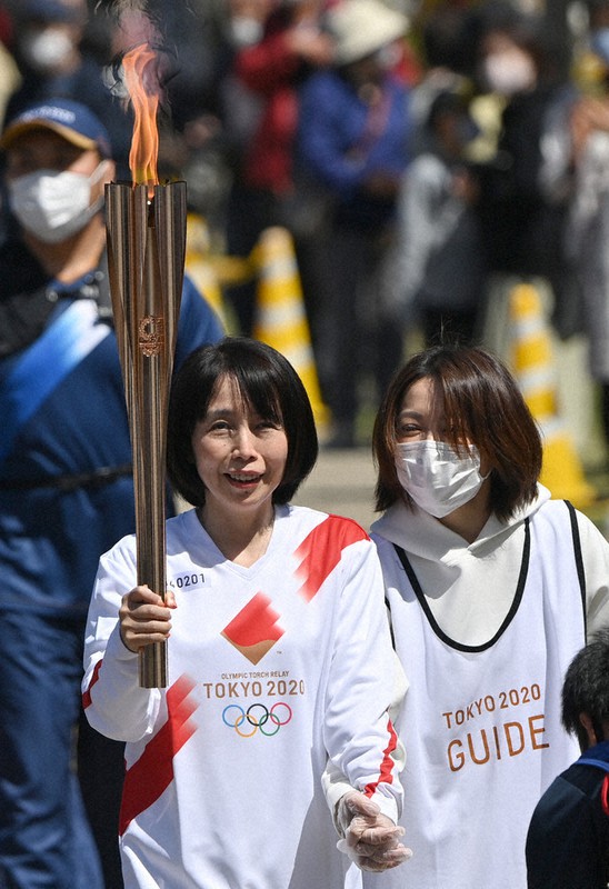 トーチを手に鈴鹿青少年の森を走る黒田智子さん(左)=三重県鈴鹿市で2021年4月7日午前11時2分、兵藤公治撮影