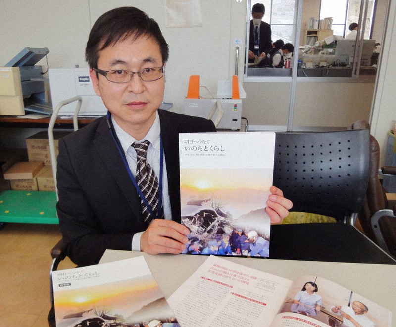 大和晃さんの両親らへのインタビューで構成した震災記録誌を手にする熊本県阿蘇市職員の佐藤祐幸さん=同市役所で2021年3月31日午後3時49分、山本泰久撮影