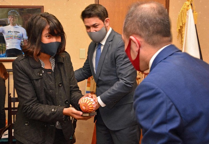 臥雲義尚市長(右)から記念品を受け取るロサフレテさん。中央は高田ロバート大使=長野県松本市役所で2021年4月7日、武田博仁撮影