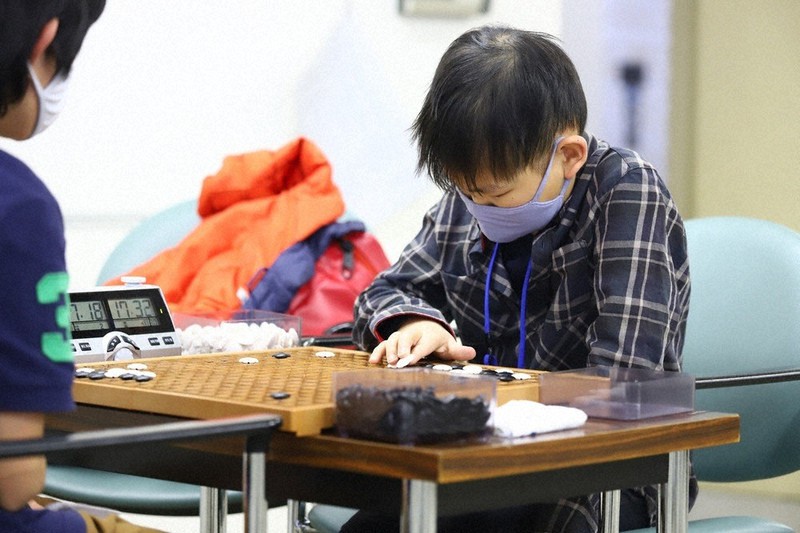 視覚障害者用の碁盤と碁石を使って対局する岩崎晴都さん(右)=日本棋院提供