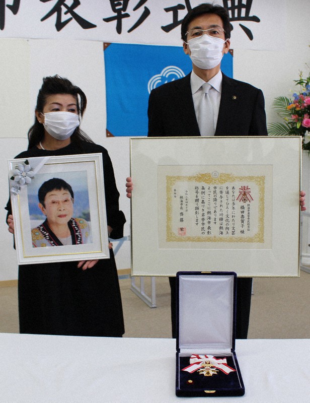 三原牧子秘書(左)が遺影を持つ橋田寿賀子さんに斉藤栄・熱海市長(右)から称号記と名誉市民章が贈られた=静岡県熱海市役所で2021年4月10日、梁川淑広撮影