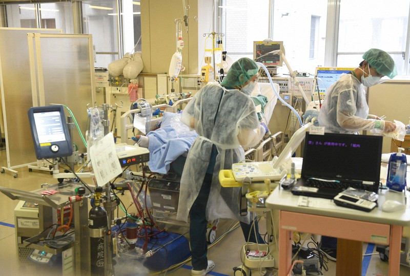 重症者の治療に使われる人工心肺装置「ECMO(エクモ)」が稼働する病室で患者のケアにあたる看護師ら=福岡市城南区の福岡大病院で2020年12月24日、矢頭智剛撮影