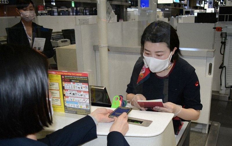 乗客のスマートフォンの画面をチェックする日本航空の地上旅客係員=成田空港で2021年4月5日、中村宰和撮影