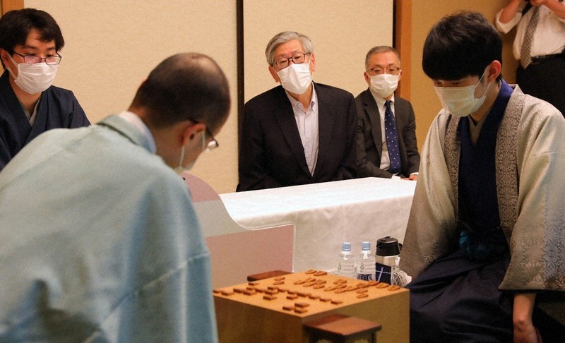 渡辺明名人(手前左)と斎藤慎太郎八段(同右)の対局を見つめる作家の松浦寿輝さん(奥中央)=東京都文京区のホテル椿山荘東京で7日、長谷川直亮撮影