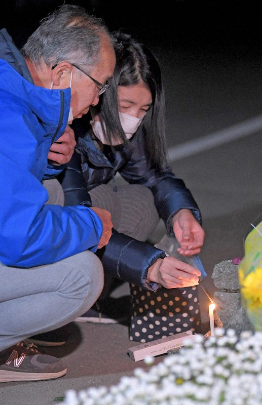 大和晃さんが見つかった阿蘇大橋の崩落現場付近で、ろうそくに火をともす母忍さん(右)と父卓也さん=熊本県南阿蘇村で2021年4月16日午前1時11分、津村豊和撮影