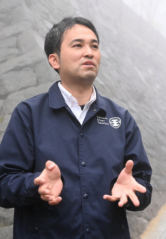 地震にも崩れず残った石垣の前で、再建への思いを語る山口雄也さん