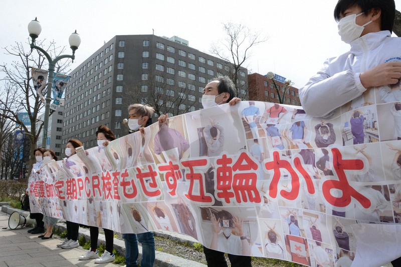 「#看護師に定期PCR検査もせず五輪かよ」と書かれた横断幕を掲げる道医労連の組合員ら=札幌市中央区で2021年4月16日午後1時1分、岸川弘明撮影