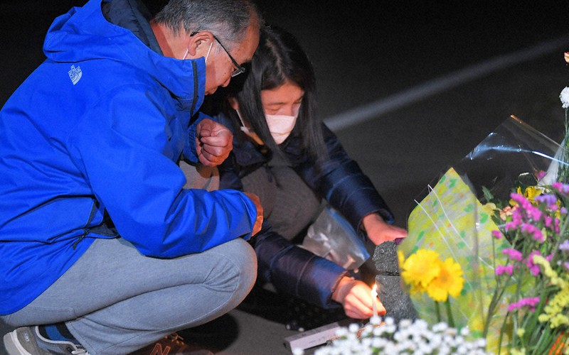 大和晃さんが見つかった阿蘇大橋の崩落現場付近で、ろうそくに火をともす父卓也さん(左)と母忍さん=熊本県南阿蘇村で2021年4月16日午前1時11分、津村豊和撮影