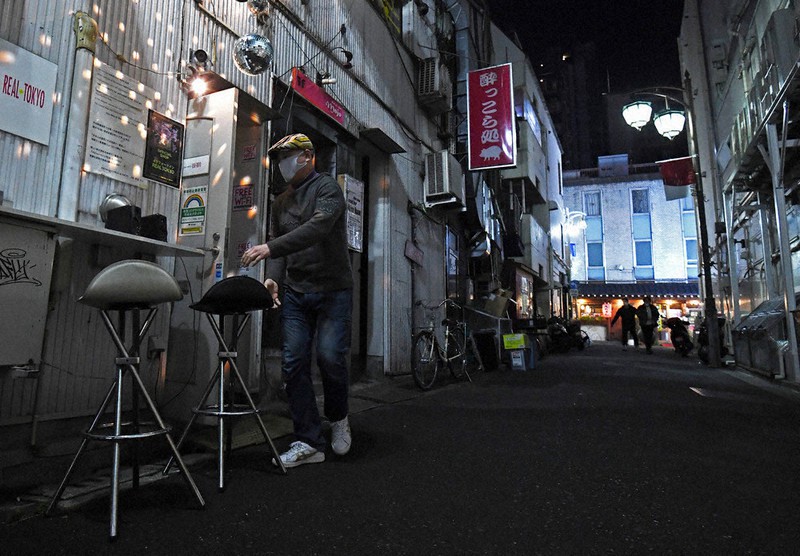 緊急事態宣言を受け、午後8時に店を閉める新宿・歌舞伎町でバーを経営する男性。表の人通りは既にまばらだった=東京都新宿区で1月8日、滝川大貴撮影