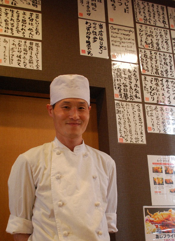 「とんかつを食べて笑顔になるきっかけになってくれれば」と話す金子友則さん。店の壁には手書きの「名言」も=奈良市神殿町の「まるかつ本店」で、中田博維撮影
