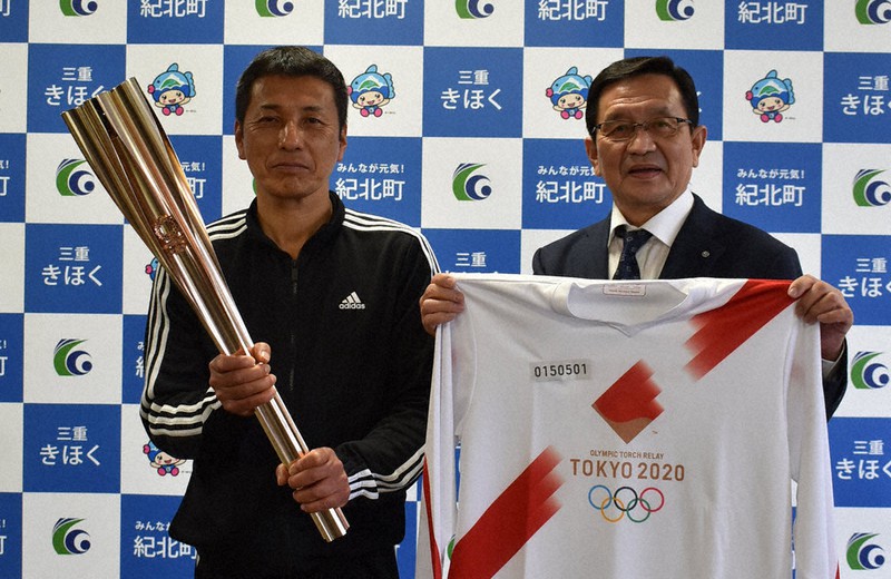 聖火ランナーを務めた石倉優一さん(左)からトーチとユニホームの寄贈を受けた尾上寿一町長=三重県紀北町役場で、2021年4月16日、下村恵美撮影