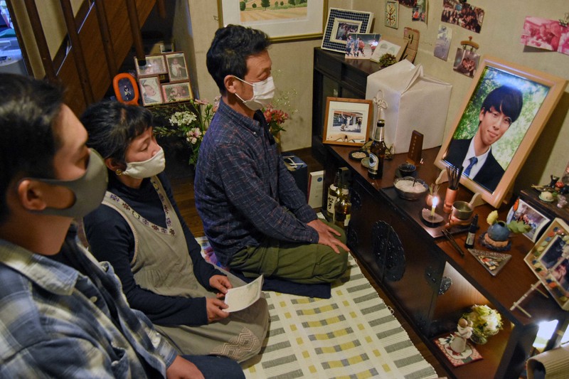 大野睦さんの遺影を見つめる(左から)兄太地さん、母久美子さん、父浩介さん=東京都内で2021年4月16日未明、関谷俊介撮影