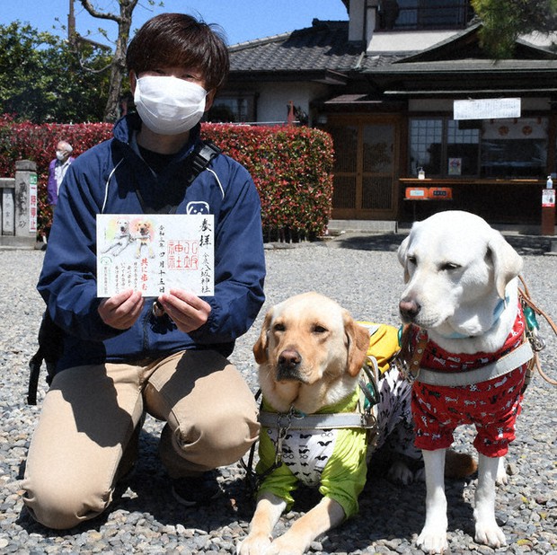 点字付きの御朱印を手にする久野さん(左)と協会のPR犬=宇都宮市今泉4の今泉八坂神社で2021年4月15日、玉井滉大撮影