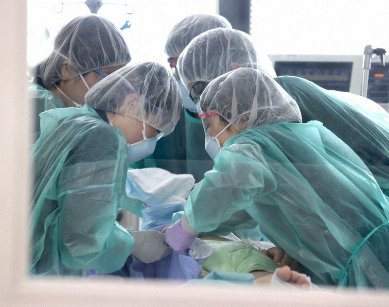 集中治療室(ICU)で新型コロナウイルスに感染した重症患者を持ち上げる看護師や医師。「第3波」で感染者が増えた1月は多い日で6人もの重症患者が入院していた=3月31日