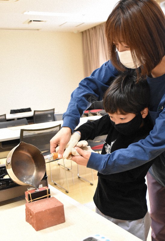 鏡の鋳型に合金を流し込む親子連れ=小松市原町の市埋蔵文化財センターで2021年4月24日午前10時29分、井手千夏撮影