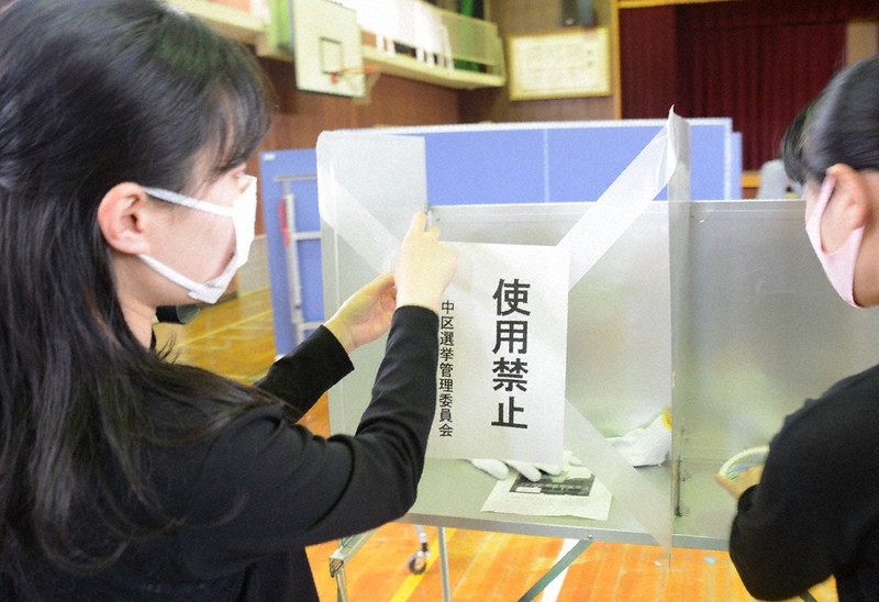 投票所が「密」にならないよう、一部の記載台に「使用禁止」の紙を貼る職員たち=中区の広島市立幟町小で2021年4月24日午前10時26分、池田一生撮影