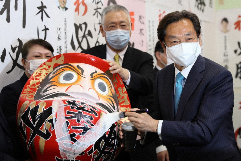 当選が確実となり、だるまにVサインを書く松木謙公氏(右)=札幌市北区で2021年4月25日午後8時18分、貝塚太一撮影