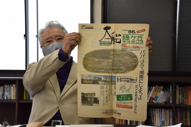 売り出し当時の広告を広げてみせる吉井信幸さん=横浜市で、筆者撮影