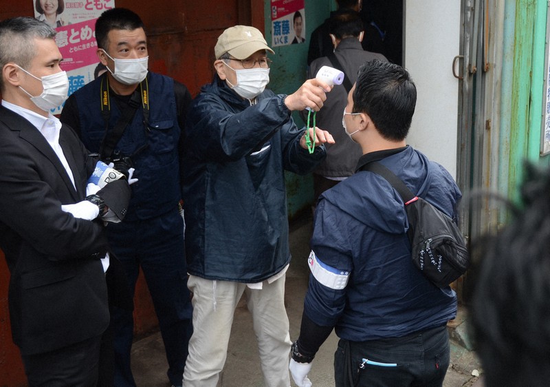 捜索に入る前に中核派の関係者(右から2人目)から検温される警視庁の捜査員=東京都江戸川区松江1で2020年10月16日午前8時25分、斎藤文太郎撮影