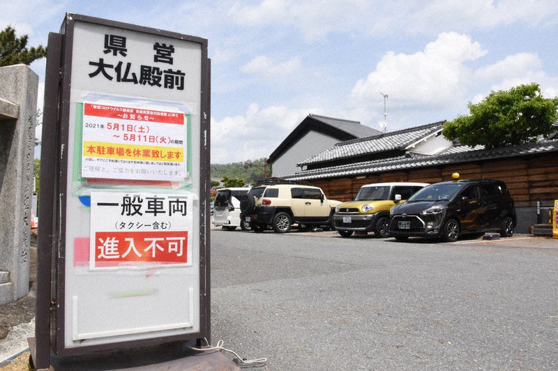 県営大仏殿前駐車場の休業を知らせる張り紙。近くの民間駐車場には県外ナンバーの車が並んだ=奈良市で2021年5月1日午後0時20分、林みづき撮影