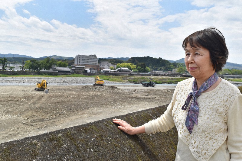 九州豪雨で氾濫し、重機での川底の土砂撤去が進む球磨川を見つめる鳥飼香代子さん=熊本県人吉市で2021年4月27日午後0時20分、城島勇人撮影
