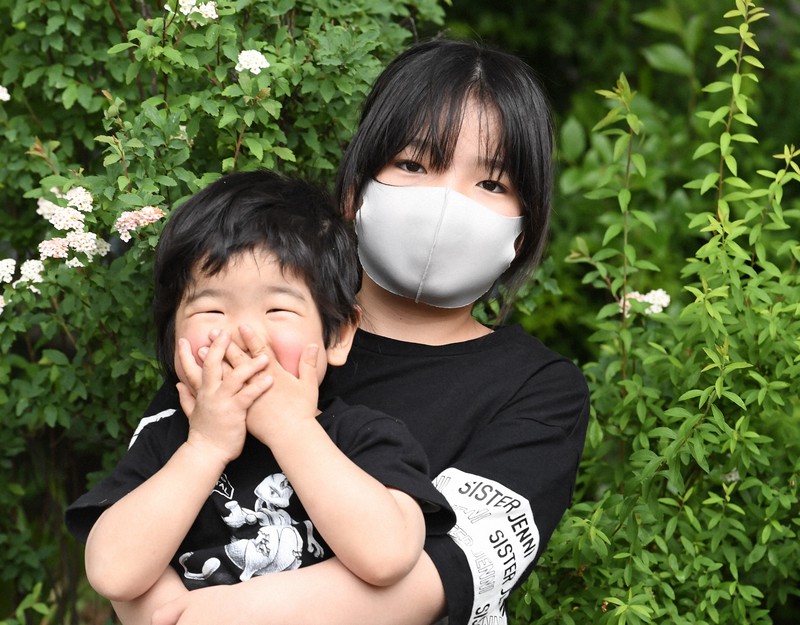図書館の前で弟を抱く小学5年生の河野柚希さん=東京都武蔵野市で2021年5月1日、竹内紀臣撮影