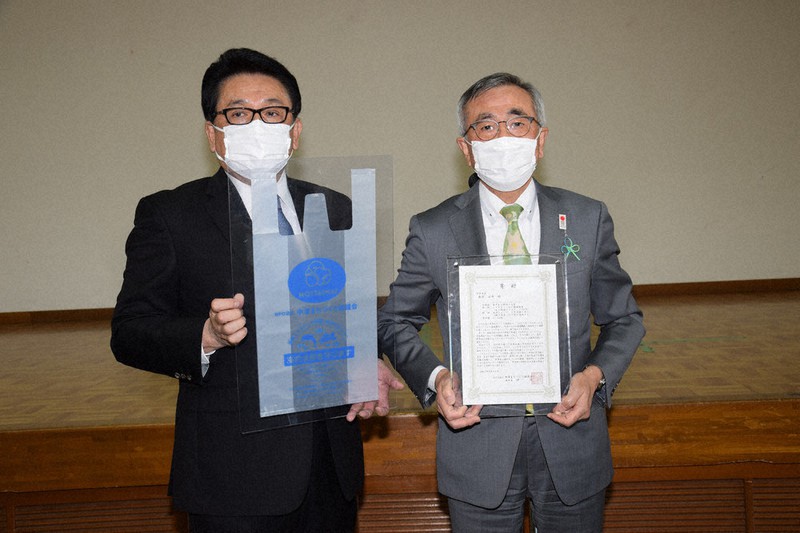 奥塚市長(右)に海中で分解する国内初のレジ袋を贈った仲理事長=大分県中津市で2021年4月20日午後2時3分、宮本勝行撮影