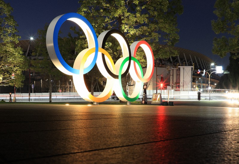 ライトアップされる五輪マーク。後方の国立競技場は夜の闇に落ちたままだ=東京都新宿区で2021年1月18日、梅村直承撮影