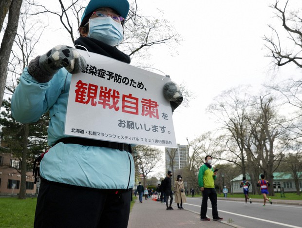 東京オリンピックのマラソンテスト大会で、北海道大構内を選手が走る中、観戦自粛を呼びかけるボランティア=札幌市北区で2021年5月5日午前10時55分、貝塚太一撮影