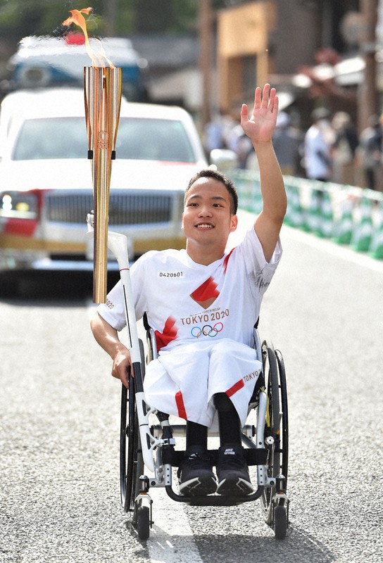 車いすで聖火をつなぐ内田琢馬さん=佐賀県有田町で9日(代表撮影)