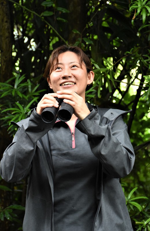 奄美大島の山で野鳥を追う伊藤さん。「すぐ後ろの山でルリカケスが鳴いているほど人と自然が近い」と話す=2021年5月8日午後3時17分、神田和明撮影