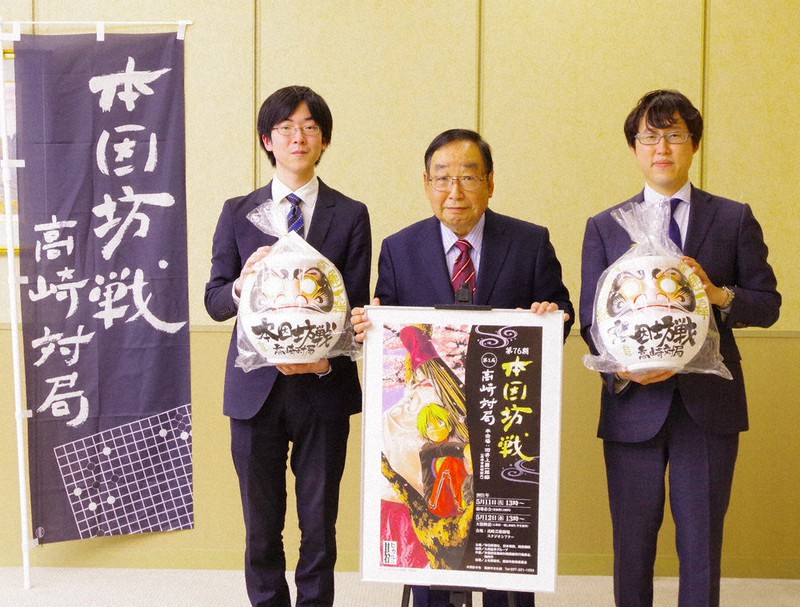 富岡賢治市長(中央)をはさんで「本因坊戦高崎対局」のだるまを手にする芝野虎丸王座(左)と本因坊文裕=群馬県高崎市で2021年5月10日、佐藤伸撮影