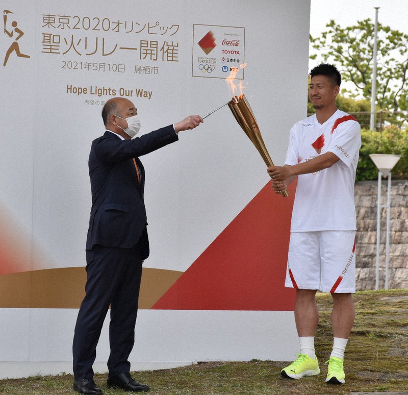 橋本康志鳥栖市長(左)から、サガン鳥栖の豊田選手の持つトーチに聖火がともされた