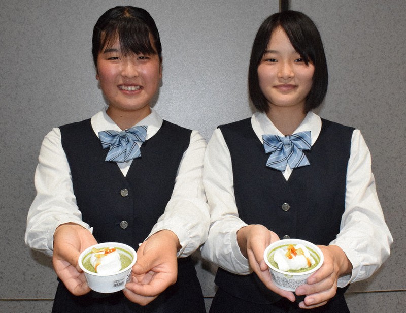 商品化された「霧茶チーズケーキ」と手にする霧島高校3年の小島さんと藤田さん(右)