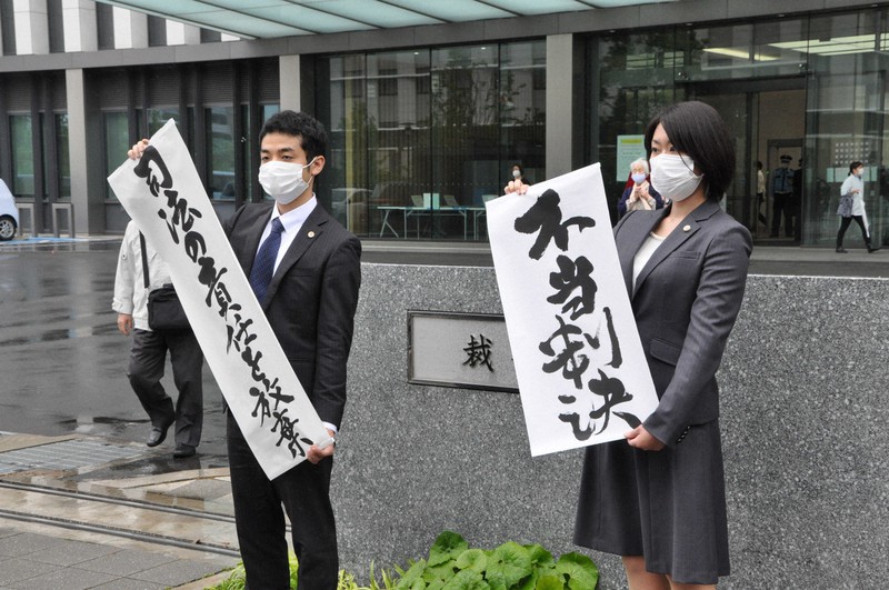 「不当判決」の紙を掲げる原告側の弁護士ら=福岡市中央区の福岡地裁前で2021年5月12日午後2時8分、平塚雄太撮影