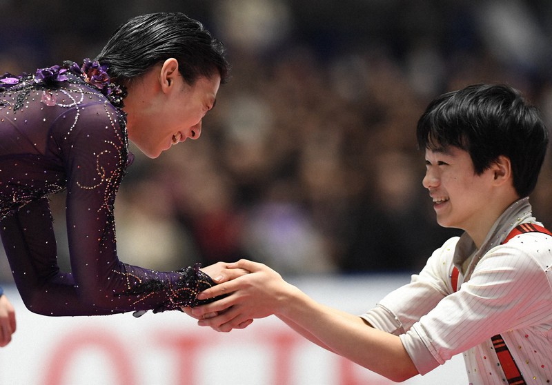 2019年全日本選手権の表彰式のステージに上がる前に、男子シングルで3位になった鍵山優真(右)に握手を求められ、笑顔で応じる羽生結弦=東京・国立代々木競技場で2019年12月22日、竹内紀臣撮影