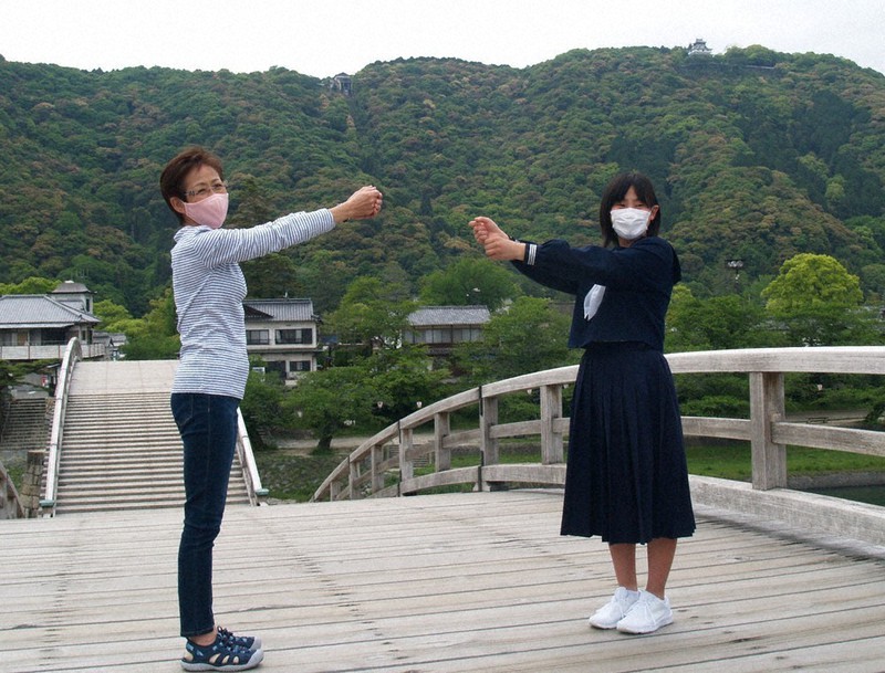 錦帯橋上で、聖火を掲げたつもりでトーチキスの所作をする三浦さん(左)と福永さん