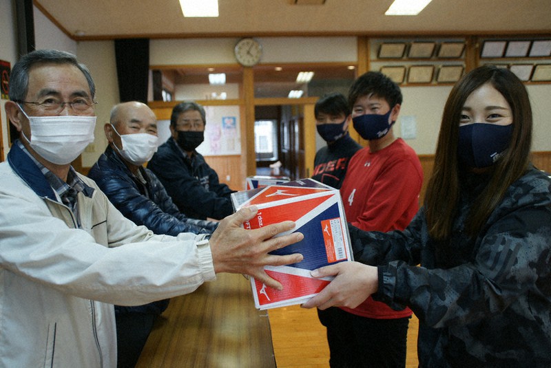 町内会員らからソフトボールを受け取る選手たち(右側)