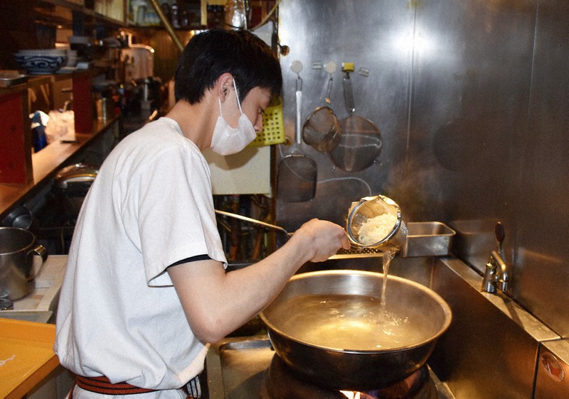 ランチ営業でうどんをゆでるスタッフ＝広島市中区の「餃子家　龍」で、根本佳奈撮影