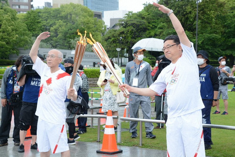 トーチキスで聖火をつなぎ、ポーズをとる野田衛さん(左)=広島市中区の平和記念公園で、小山美砂撮影