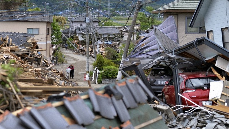 熊本地震で倒壊した家屋の間を縫うように歩く人たち=熊本県益城町で2016年4月28日、猪飼健史撮影