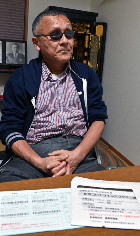 接種券(左)と封筒を前に「健康増進課から来たことかは分かるが、何の通知かは分からない」と話す菊池正光さん=福島県会津若松市で19日