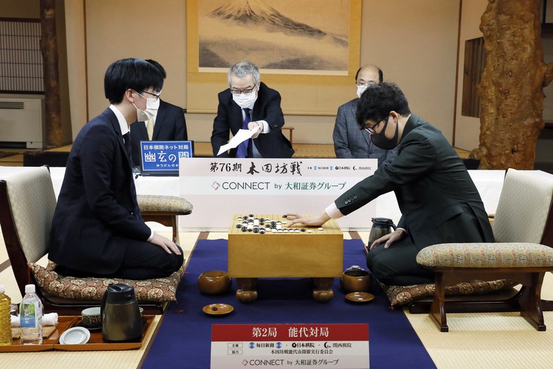 第76期本因坊決定戦七番勝負第2局2日目、封じ手を打つ本因坊文裕(右)。左は芝野虎丸王座、奥中央は立会の二十四世本因坊秀芳=秋田県能代市の旧料亭金勇で2021年5月25日午前9時4分、尾籠章裕撮影