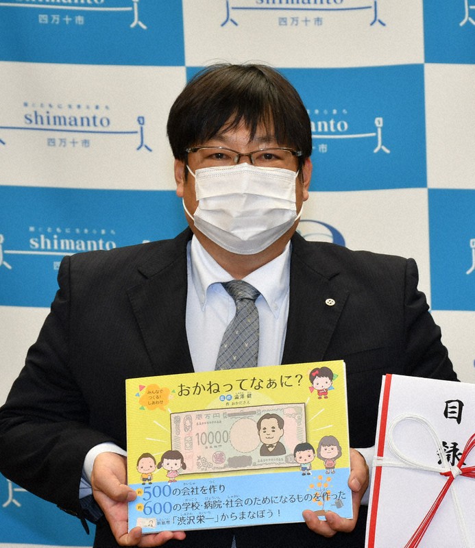 絵本を手にする田辺会長=高知県四万十市役所で、上野力撮影