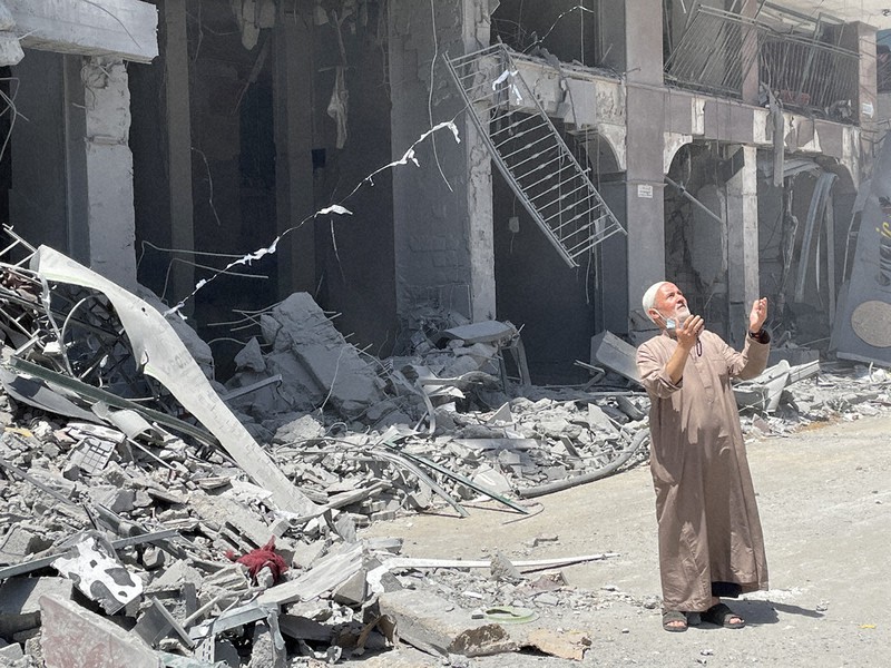 イスラエル軍にミサイルを撃ち込まれた建物の前で、天を仰いで悲しむ男性=12日