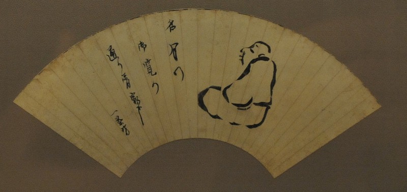 「名月のご覧の通り屑家哉」の俳句と座った姿の自画像が描かれた扇子=長野県高山村高井の一茶館で