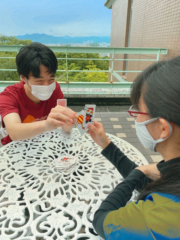 静岡市街を一望できる静岡大学の大学会館のテラスで、カードゲームを楽しむ静大生=2021年5月、ペンネーム・ひかりさん撮影