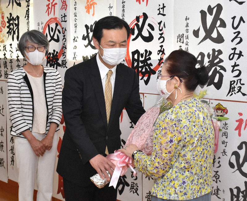 無投票で4選を決め花束を受け取る辻宏康氏(中央)=大阪府和泉市の後援会事務所で、園部仁史撮影