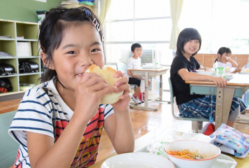 給食で地元小麦を原料にした「まあるいパン」を食べる児童たち